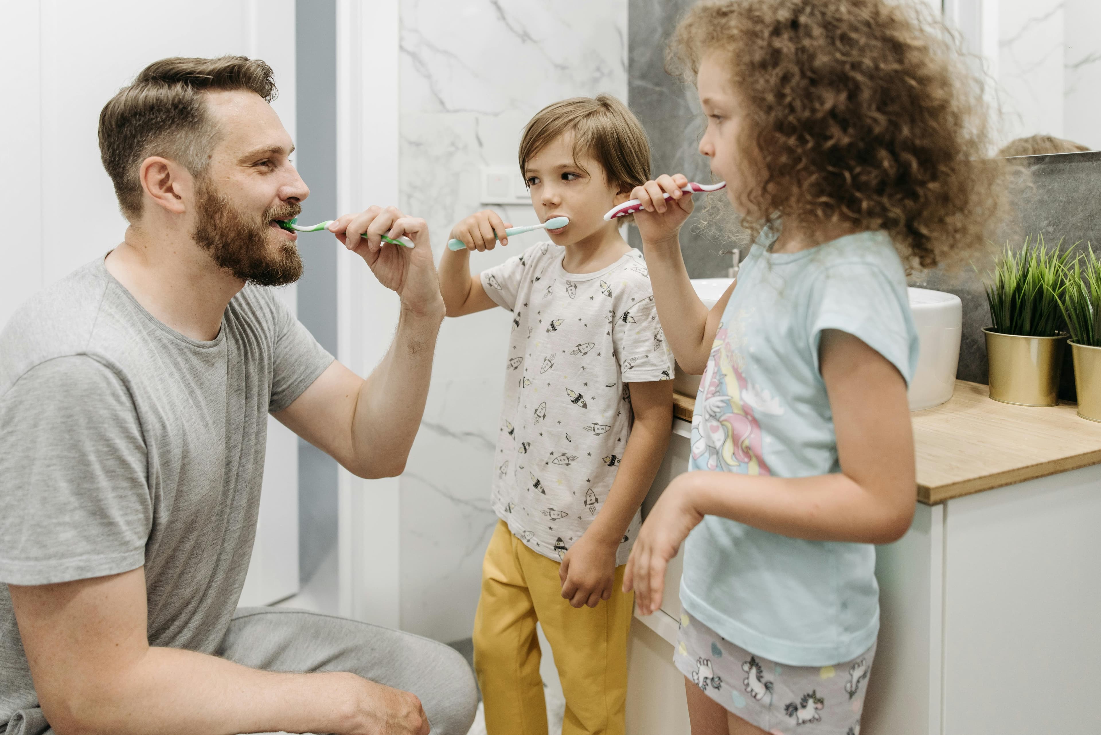 Father brushing teeth with toddler boy